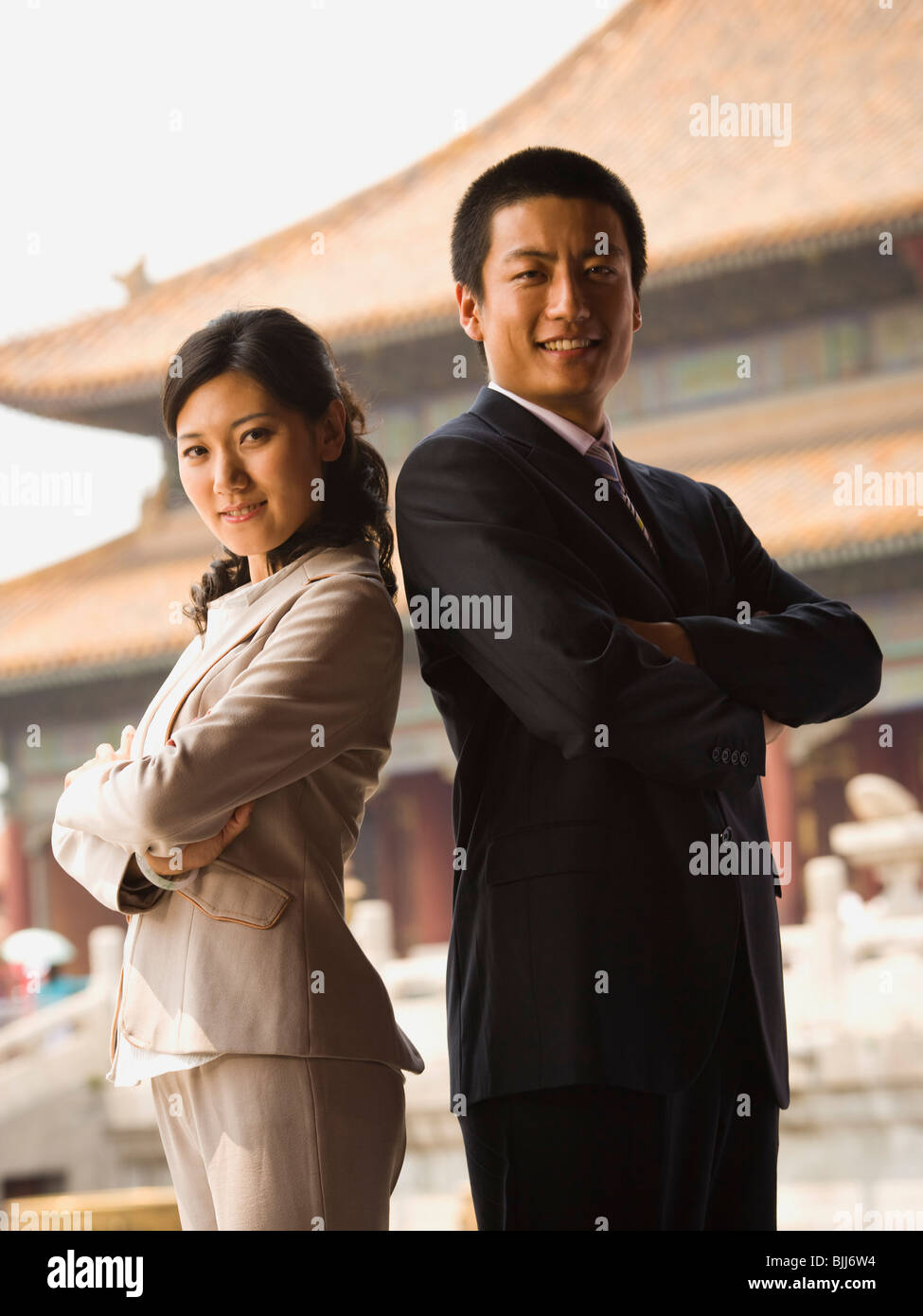 Businessman and woman standing with arms crossed et dos avec pagoda en arrière-plan Banque D'Images