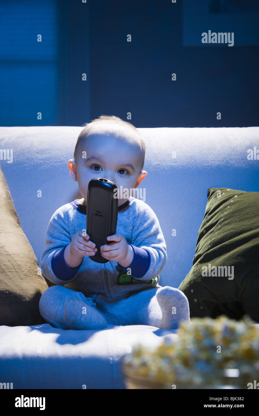 Bébé sur canapé avec télécommande de télévision Banque D'Images