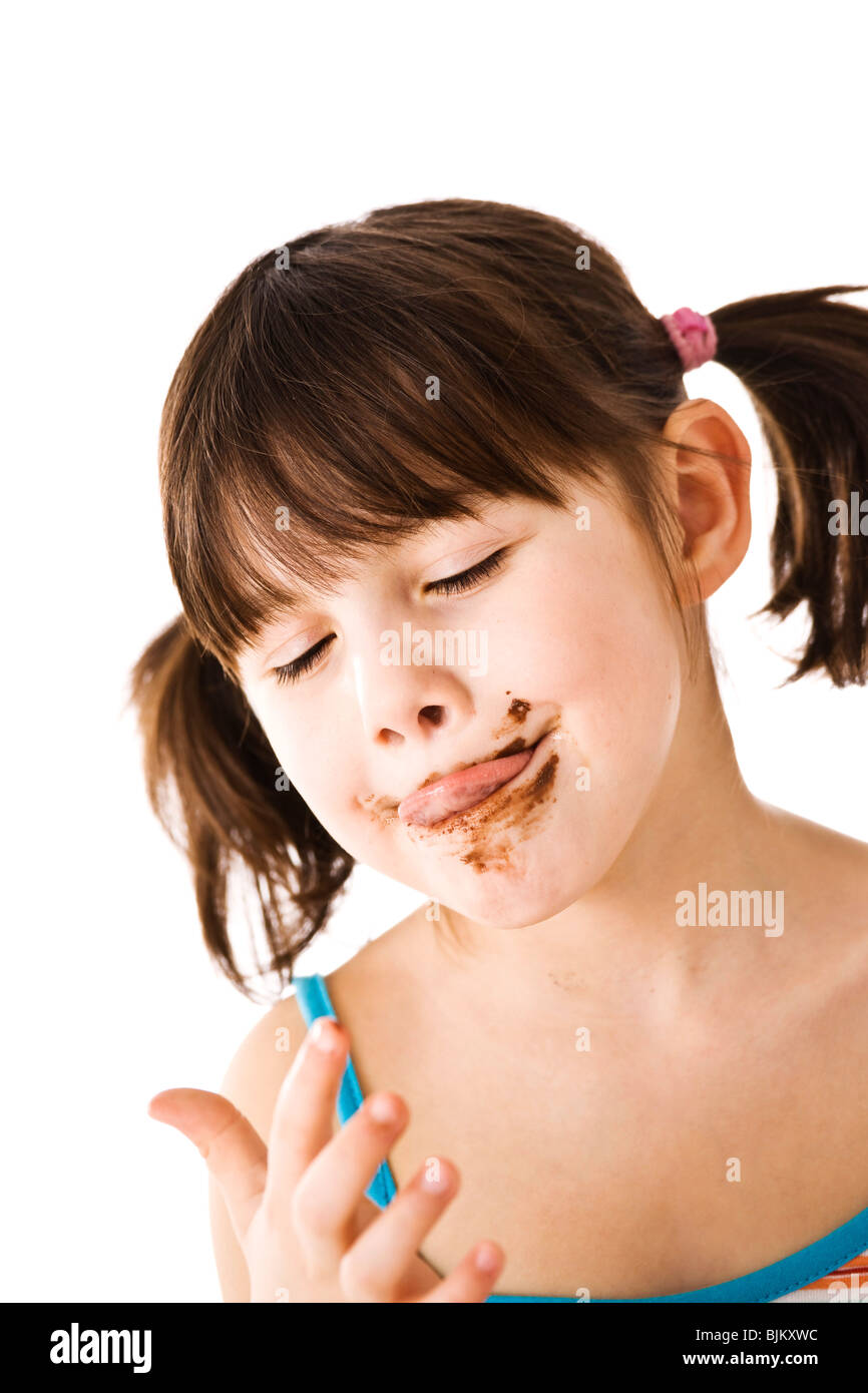 Little girl with pigtails léchant chocolat de son doigt Banque D'Images