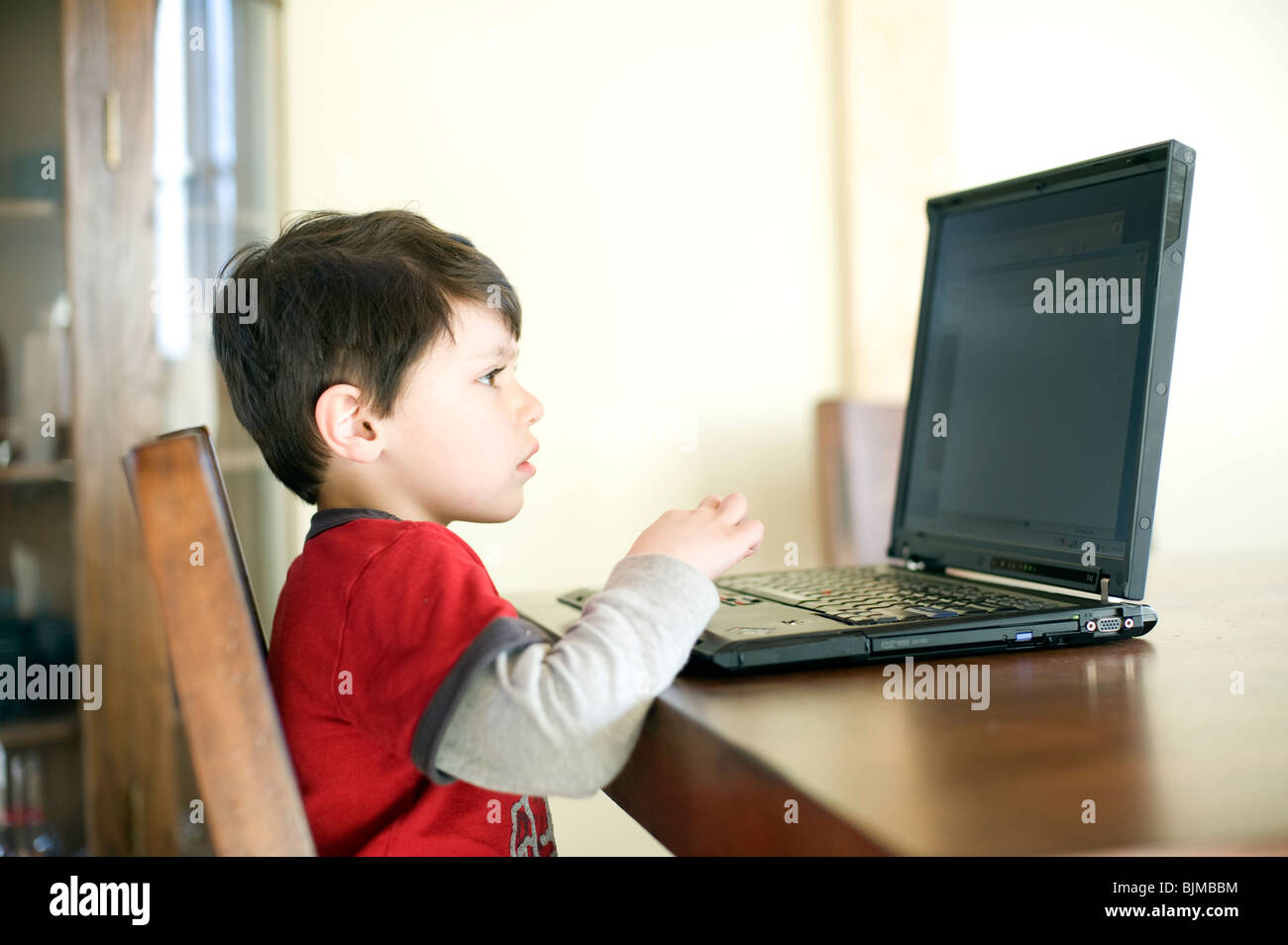 4 et 1/2 ans Hispanic boy surfe sur internet sur son ordinateur portable à la maison. Parution du modèle. Banque D'Images