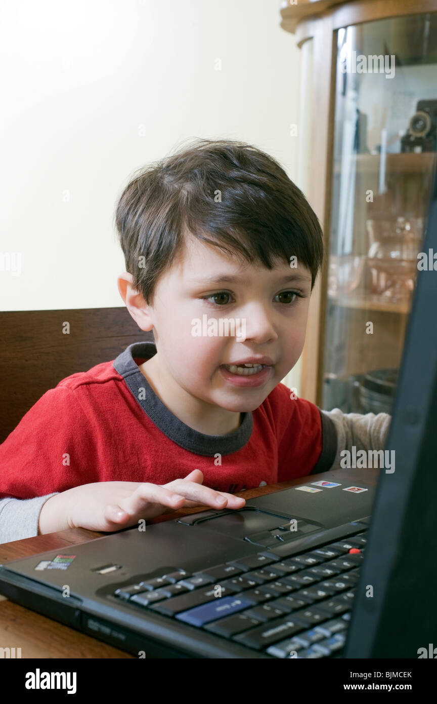 4 et 1/2 ans Hispanic boy surfe sur internet sur son ordinateur portable à la maison. Parution du modèle. Banque D'Images