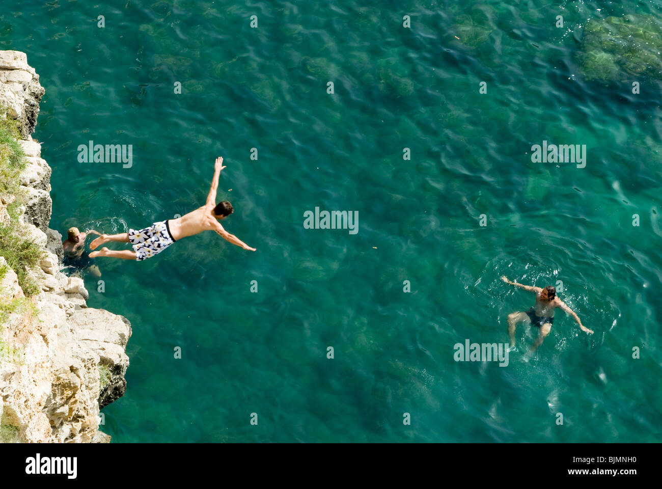 Italien, Apulien, Küste bei Polignano, junger Mann springt vom Fels ins Meer | Italie, Pouilles, jeune homme sauter dans la mer Banque D'Images