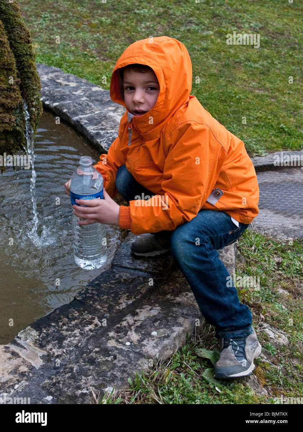 Jeune Français recueillant l'eau de source en bouteille en plastique - France. Banque D'Images