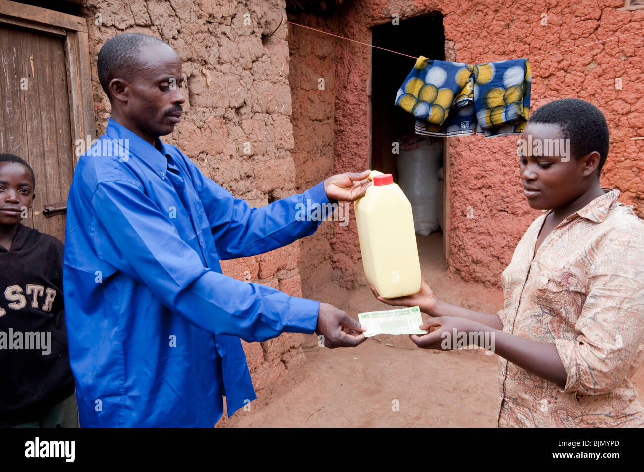 Femme de payer en espèces des agriculteurs pour le lait frais dans un village rural près de Kigali - Rwanda. Banque D'Images