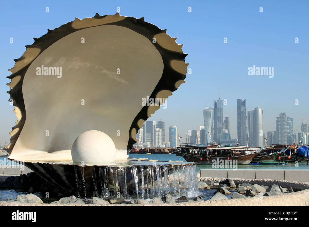 L'huître perlière et fontaine sur la corniche, dans le centre de Doha, au Qatar, avec le boutre et port la nouvelle au-delà de l'horizon. Banque D'Images