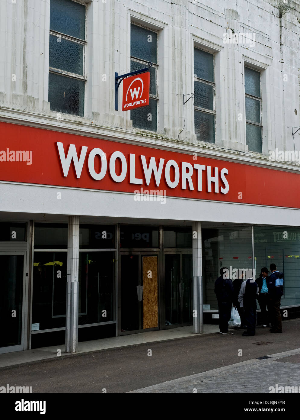 Un groupe de jeunes hommes asiatiques en dehors d'un fermé magasin Woolworths dans la rue principale à Falmouth en Cornouailles Banque D'Images
