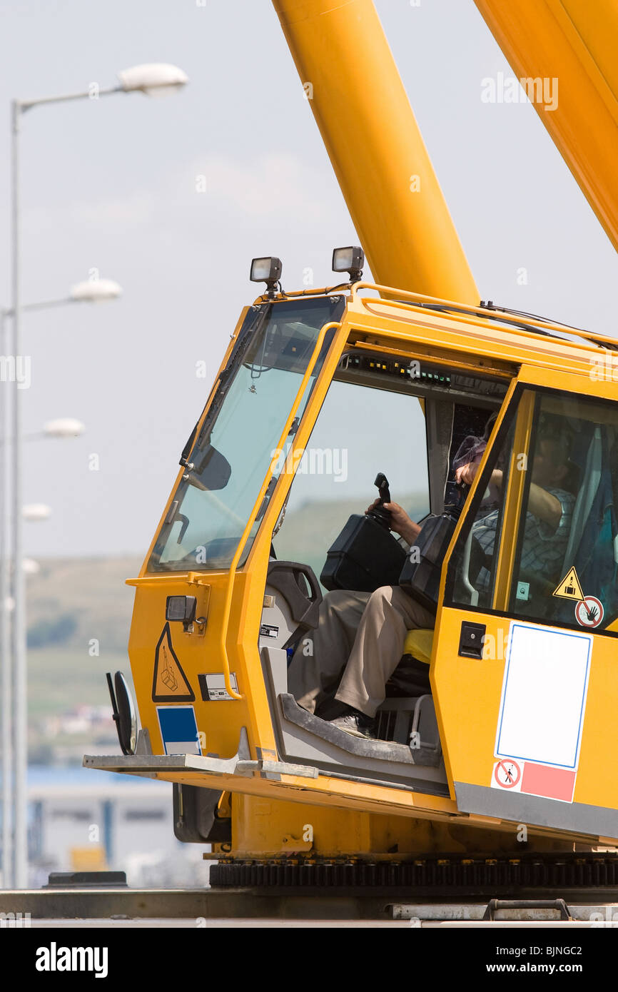 Homme conduisant une grue pour soulever certains équipements de Banque D'Images