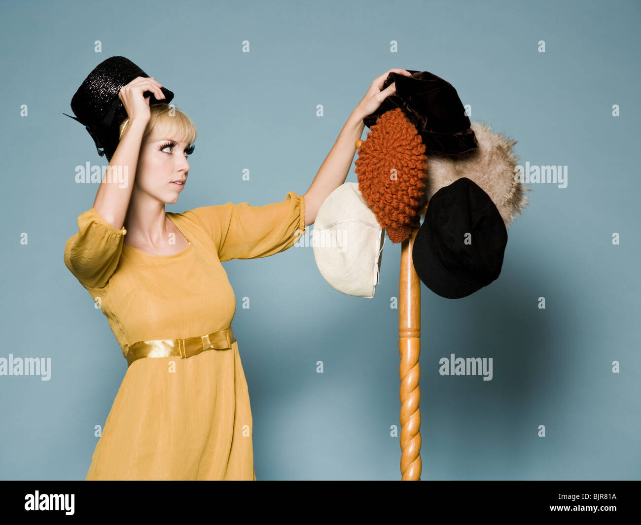 Femme en tenue des années 60 d'essayer sur différents chapeaux Photo Stock  - Alamy