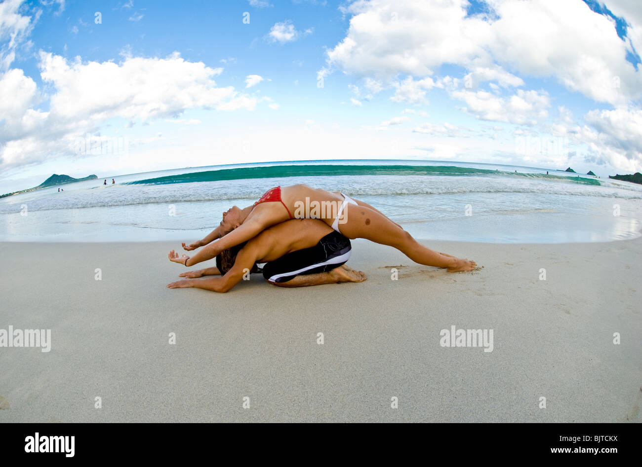 Jeune couple ( Asian man et woman) au début des années 20 faisant yoga partenaire sur plage de sable blanc en Arkansas Banque D'Images