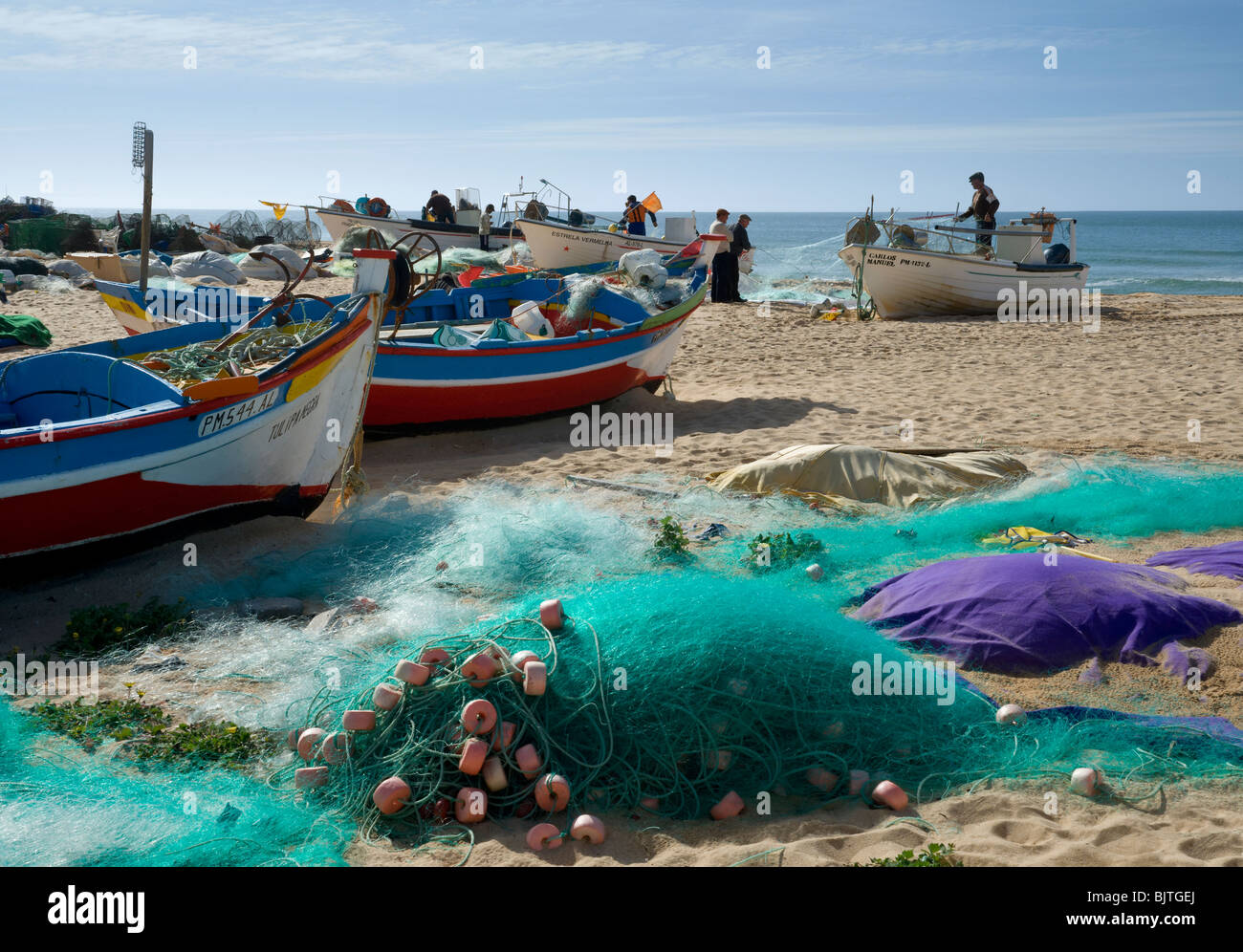 Les bateaux de pêche et pêcheurs réparant des moustiquaires ; Armacao de Pera, Algarve, Portugal, Banque D'Images