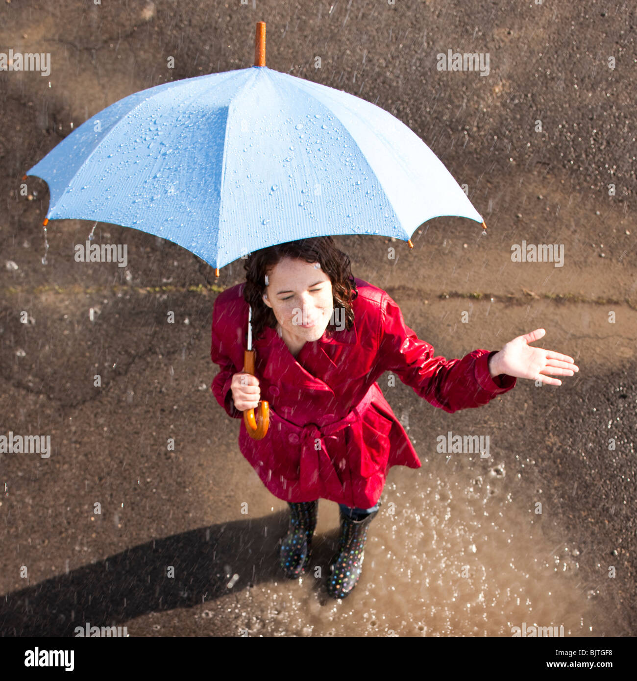 Jeune femme debout dans la pluie holding umbrella Banque D'Images