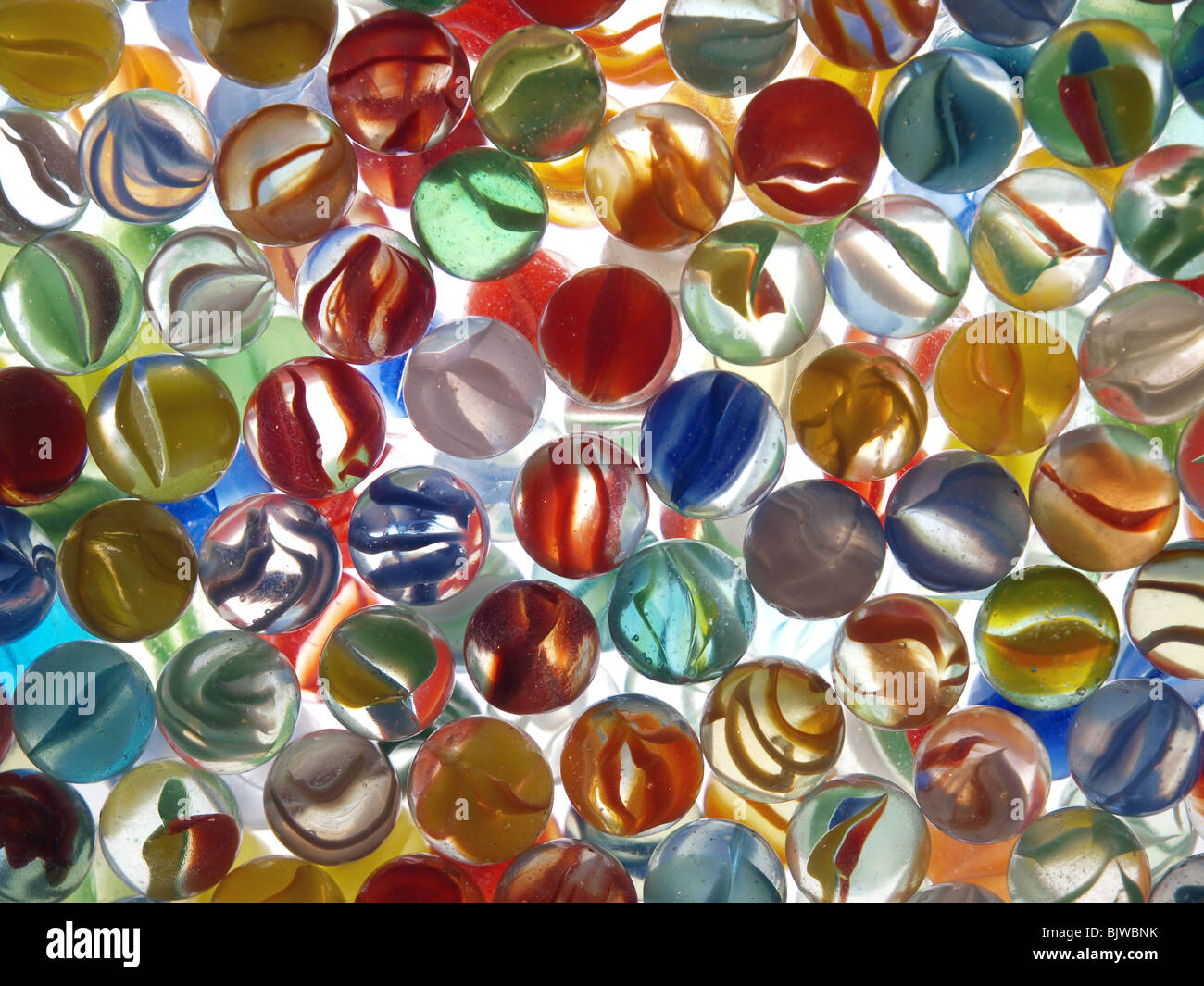 Marbres colorés dans un bol en verre sur le dessus d'une table lumineuse. Banque D'Images