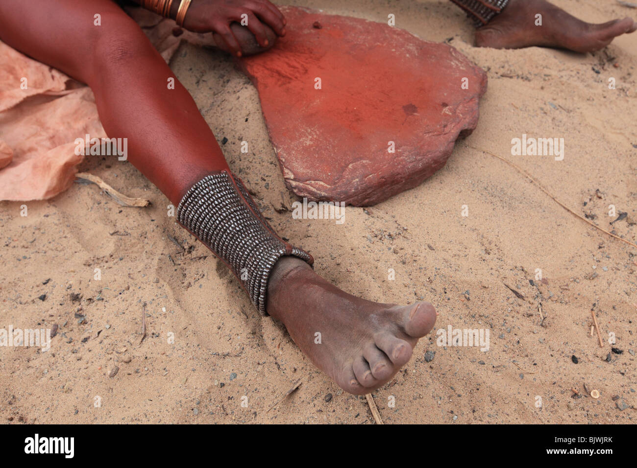 Femme Himba moud Pigment à appliquer sur la peau Banque D'Images