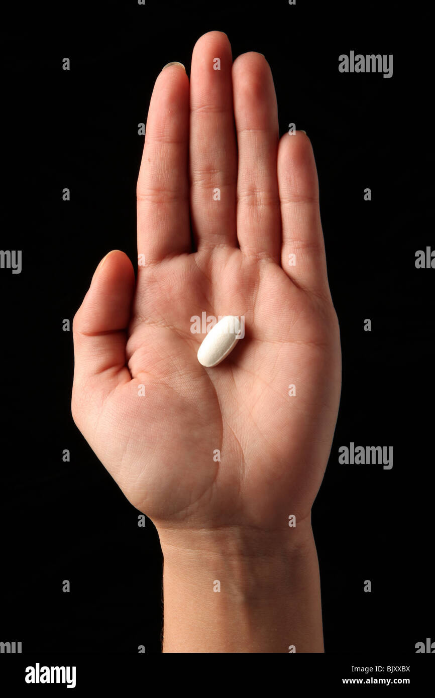 Une femme woman's hand holding une pilule dans la paume de sa main Banque D'Images