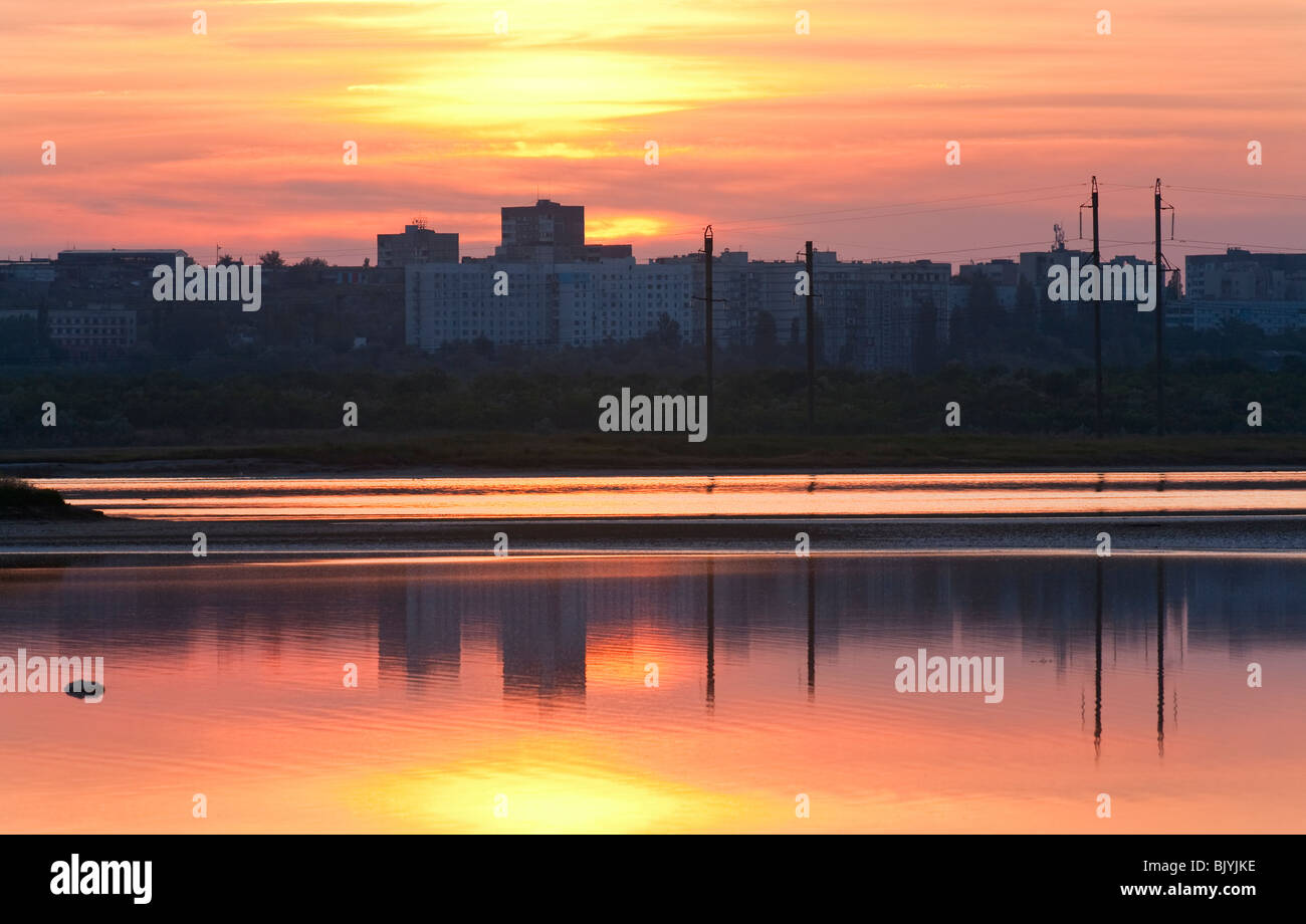 Ciel de coucher du soleil au-dessus de la ville (Scholkino, Crimea, Ukraine) et il reflet dans le lac Banque D'Images