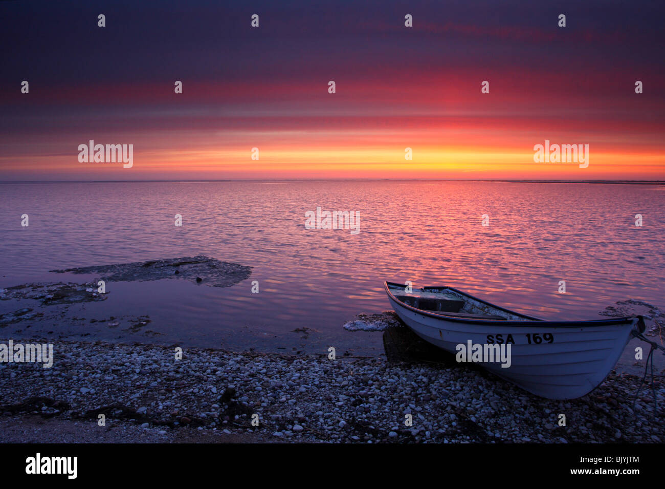 Petit bateau par la côte de la mer Baltique dans le coucher du soleil. Banque D'Images