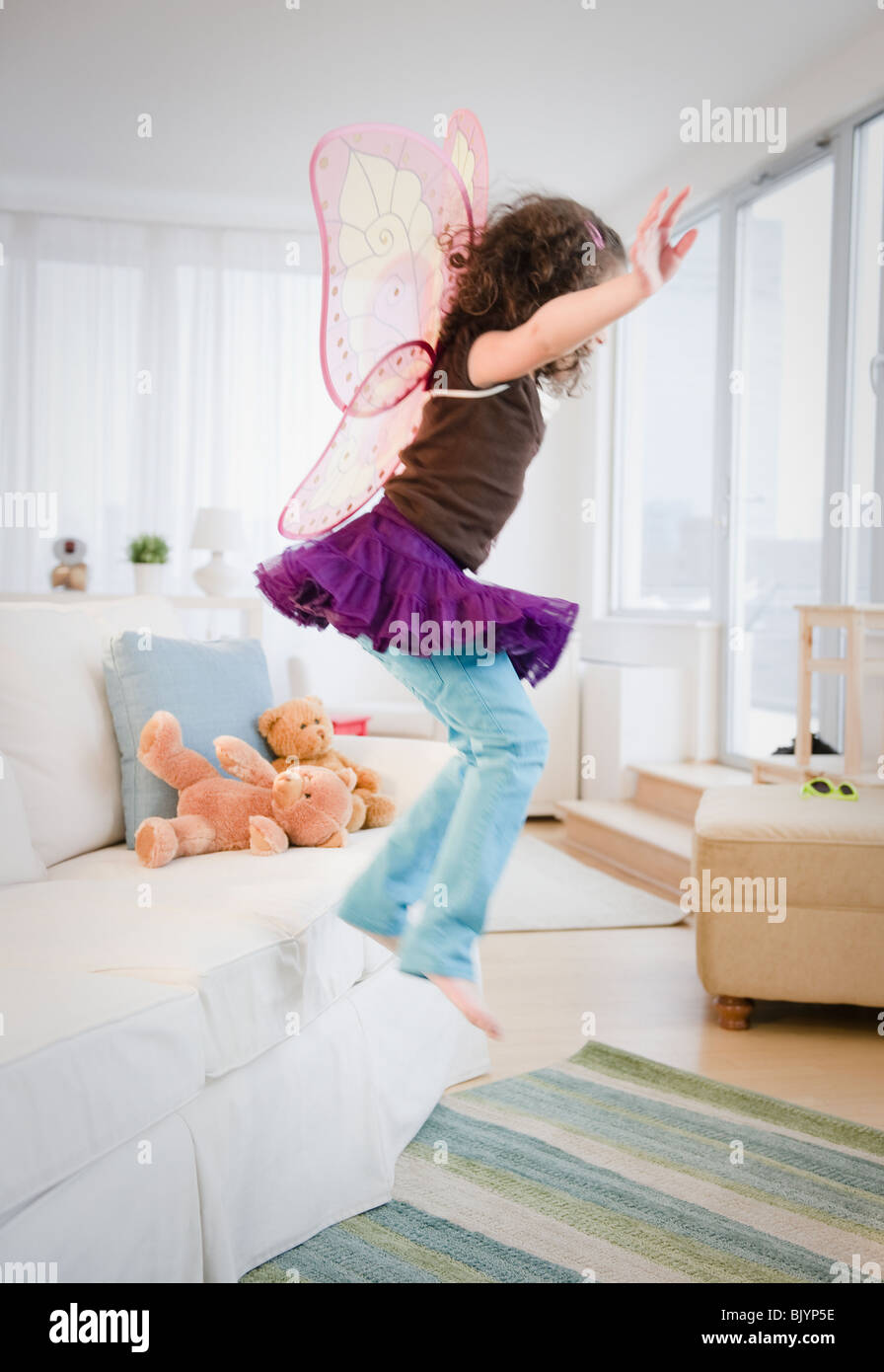 Hispanic girl in fairy wings Jumping off couch Banque D'Images