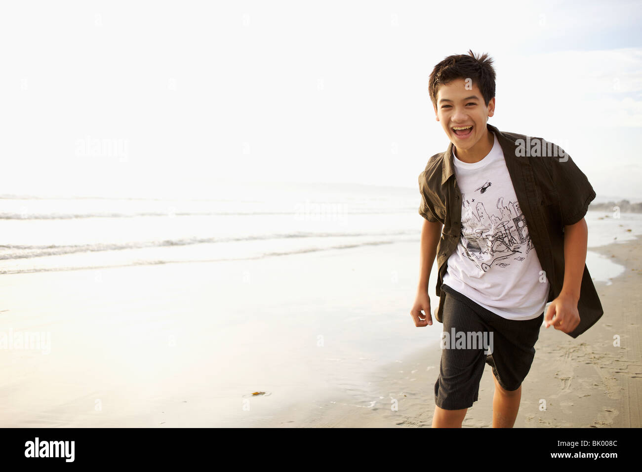 Mixed Race boy laughing on beach Banque D'Images