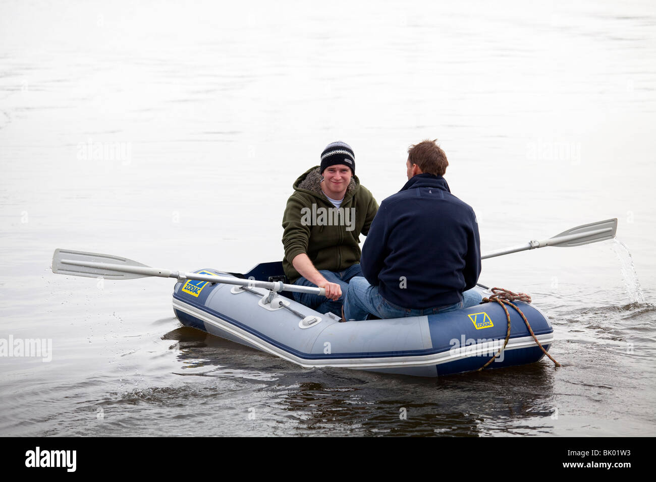 Deux hommes à l'aviron à Lymington Marina dans un canot pneumatique Zodiac Banque D'Images