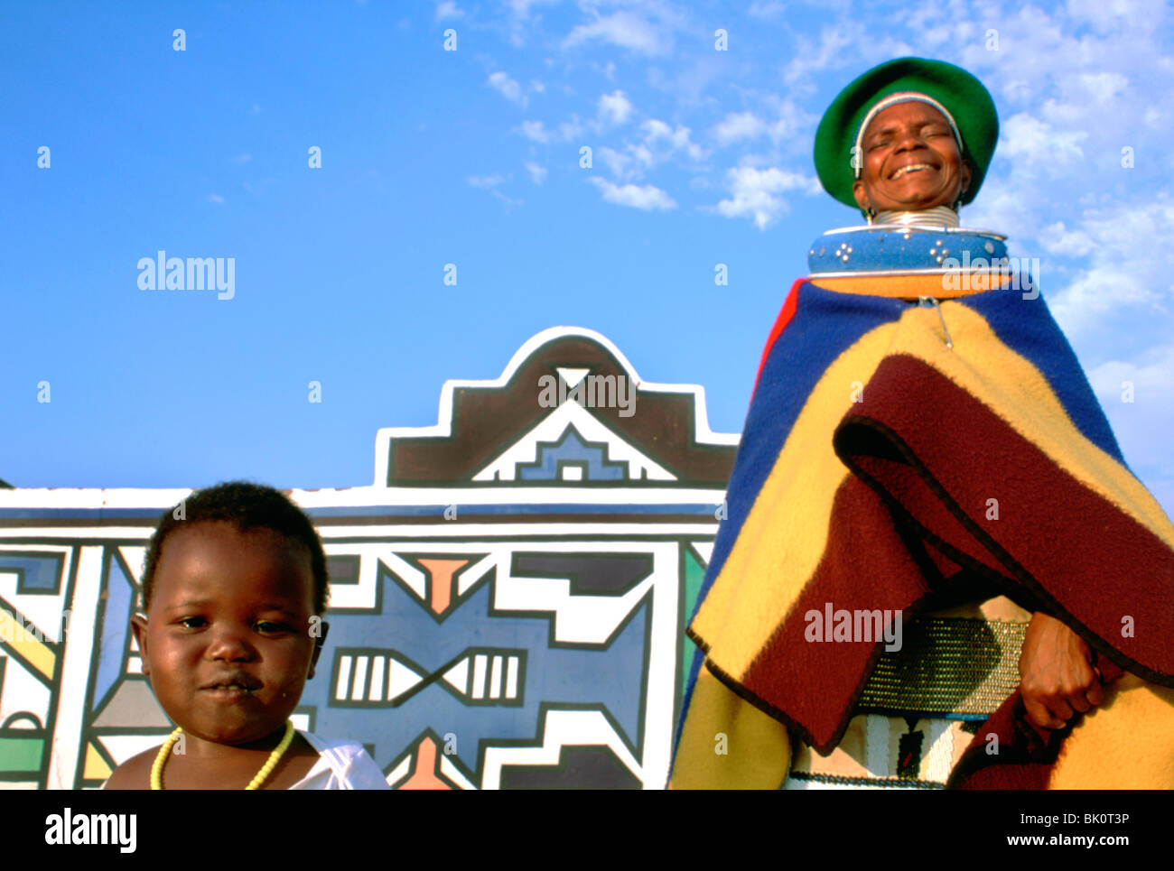 Ndebele personnes portant le costume traditionnel en face d'une maison peinte traditionnellement, l'Afrique du Sud. Banque D'Images