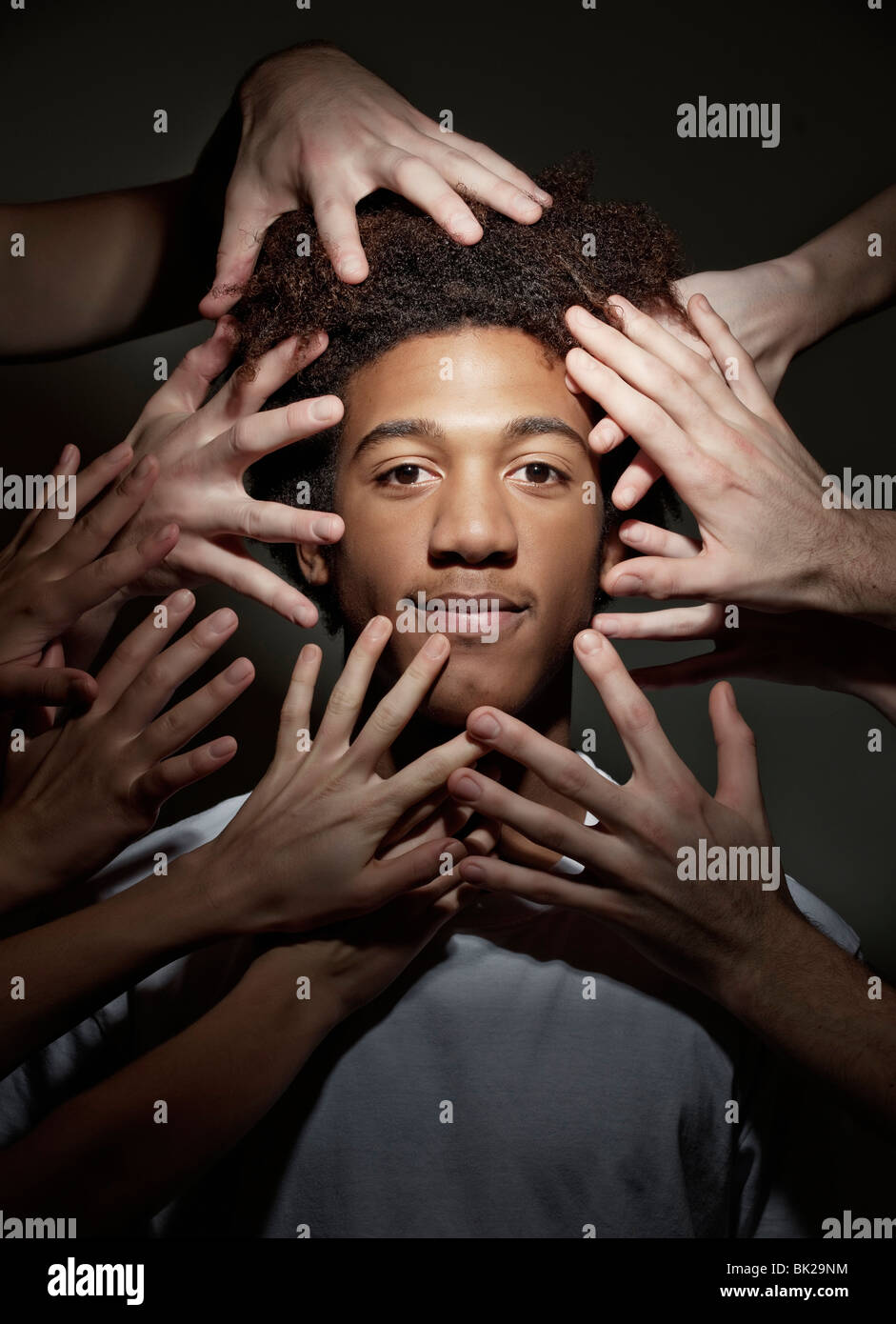 Mâle noir entouré par les mains Banque D'Images