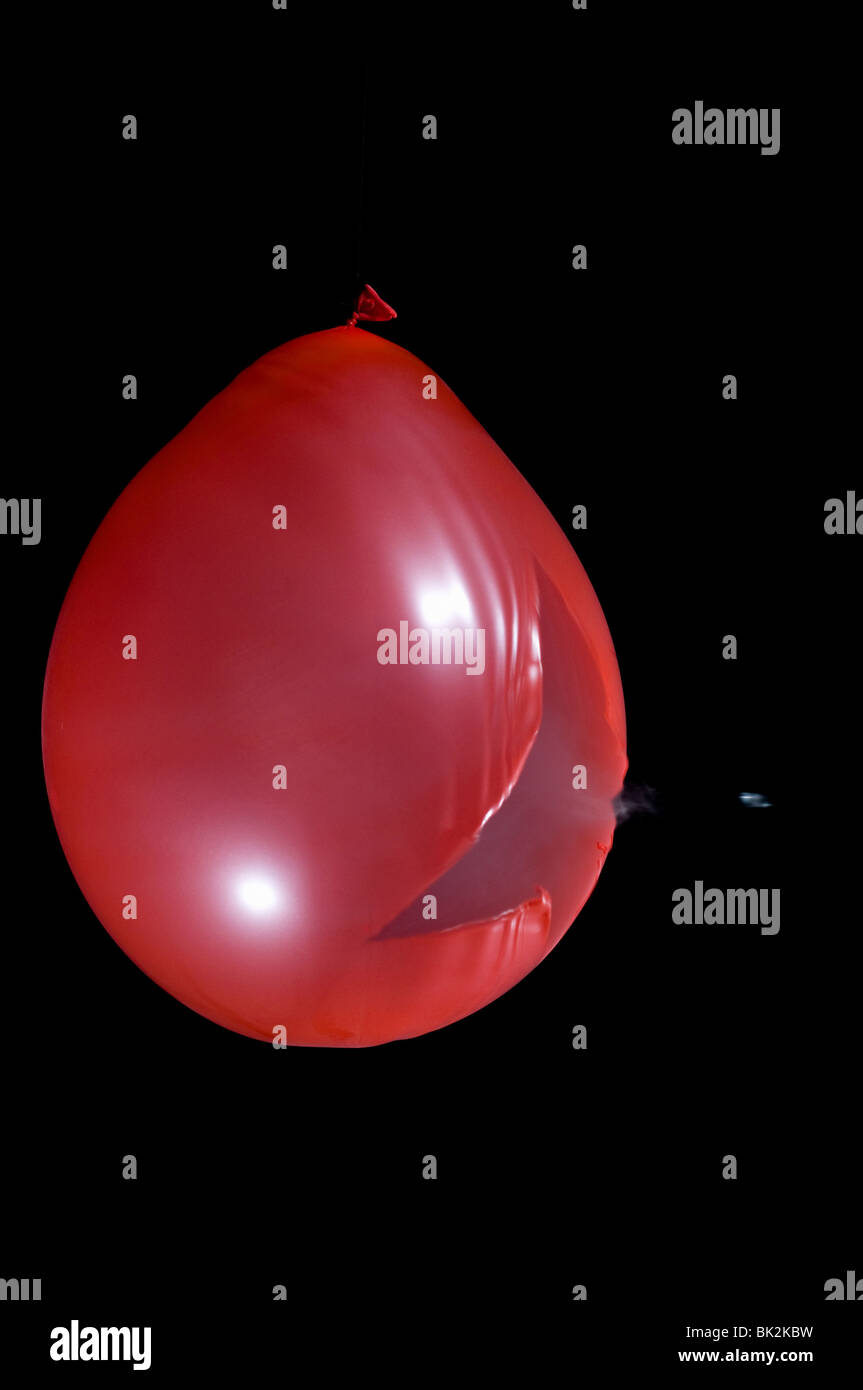 Un ballon rouge rempli de fumée lors de l'éclatement tourné avec une carabine à air. Visible à granules Banque D'Images