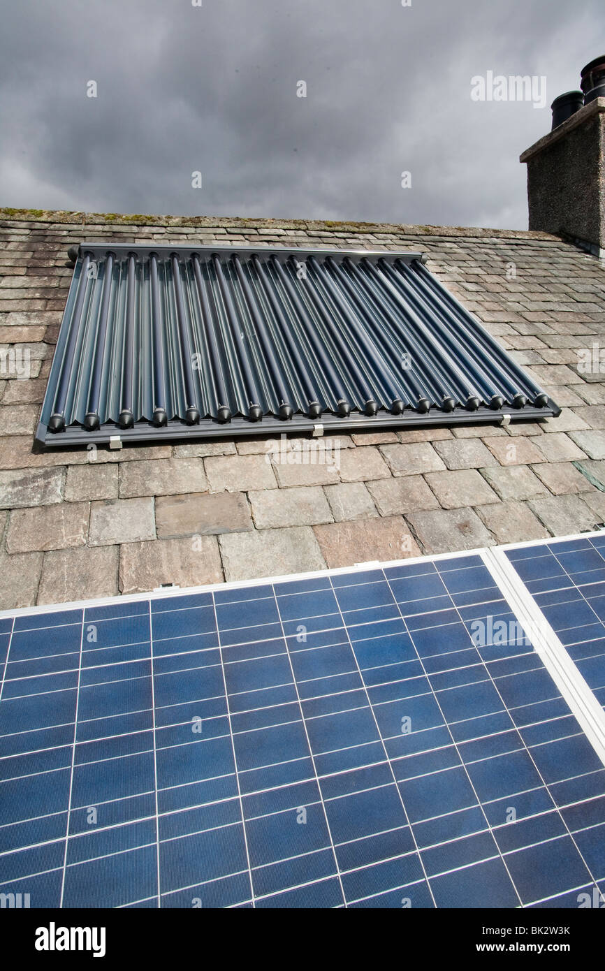 Panneaux solaires de production d'électricité photovoltaïque et eau chaude solaire panneaux sur un toit de maison à Ambleside, Cumbria, Royaume-Uni. Banque D'Images
