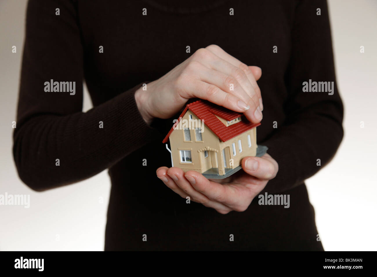 Mains tenant un modèle maison. Symbole : bien comme de l'investissement Banque D'Images