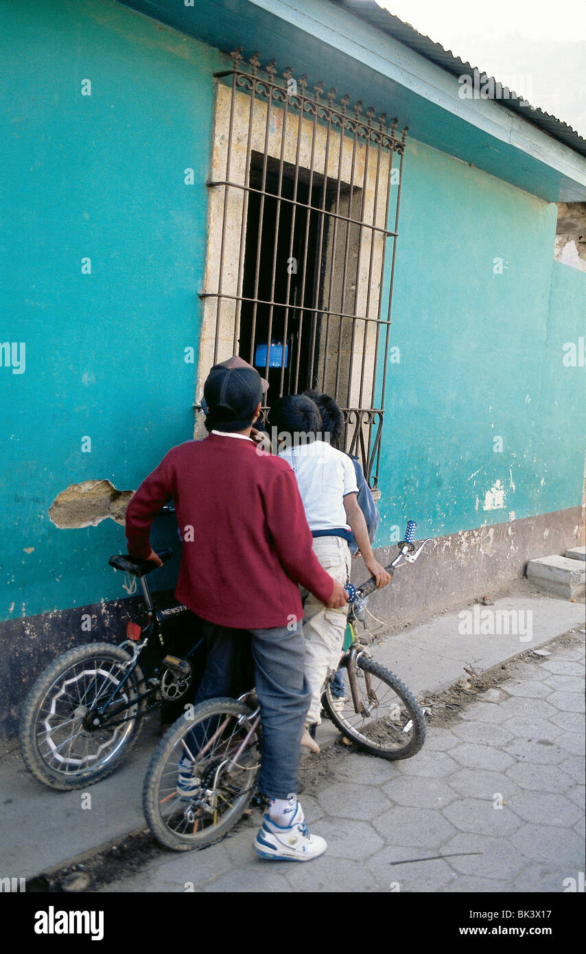 Trois enfants guatémaltèques de regarder la télévision à travers une vitre, Chopal Région, Guatemala Banque D'Images