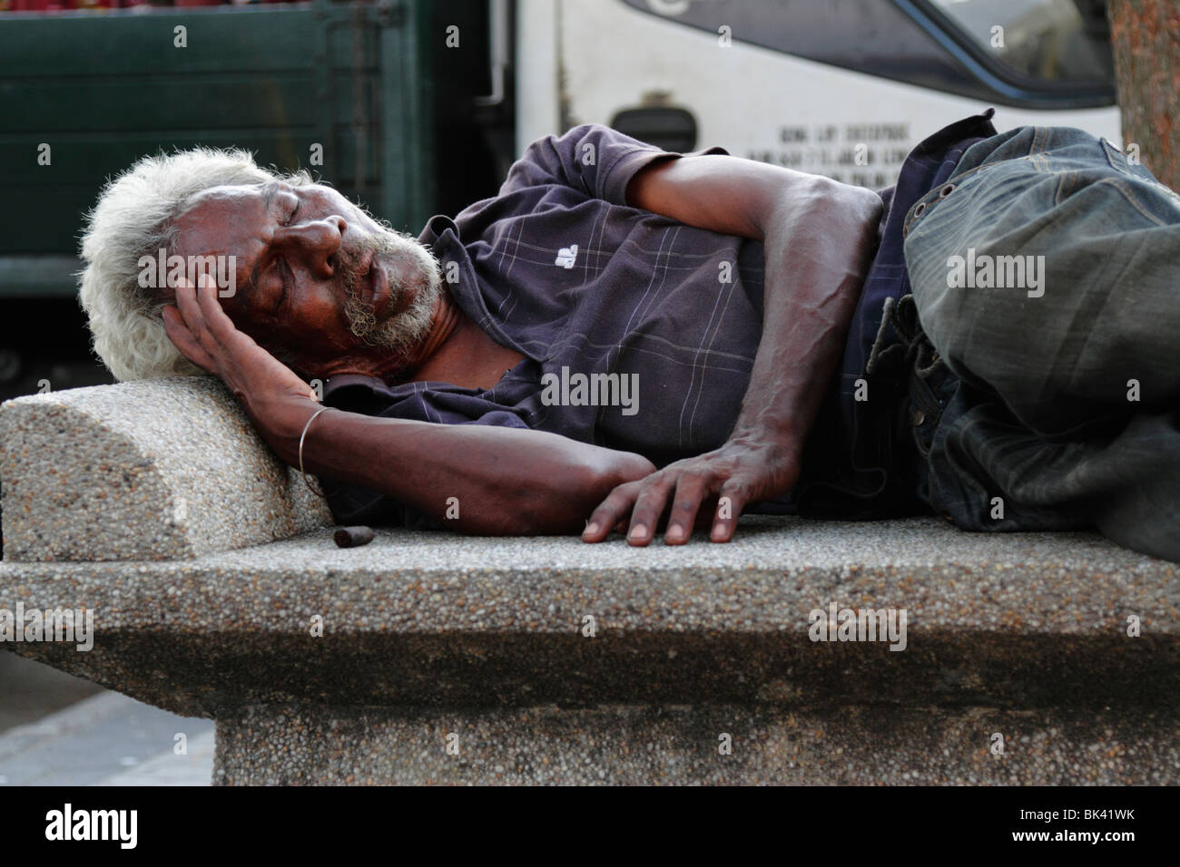Un mendiant dormant sur un banc public à Georgetown, Penang, Malaisie Banque D'Images