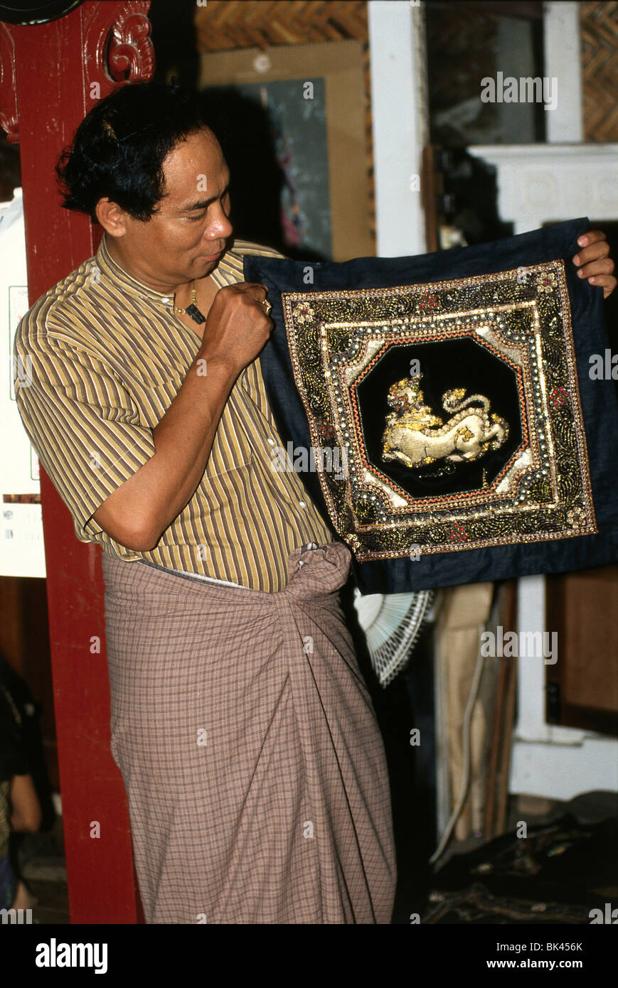 Homme tenant un birman tapisserie brodée d'or, au Myanmar Banque D'Images