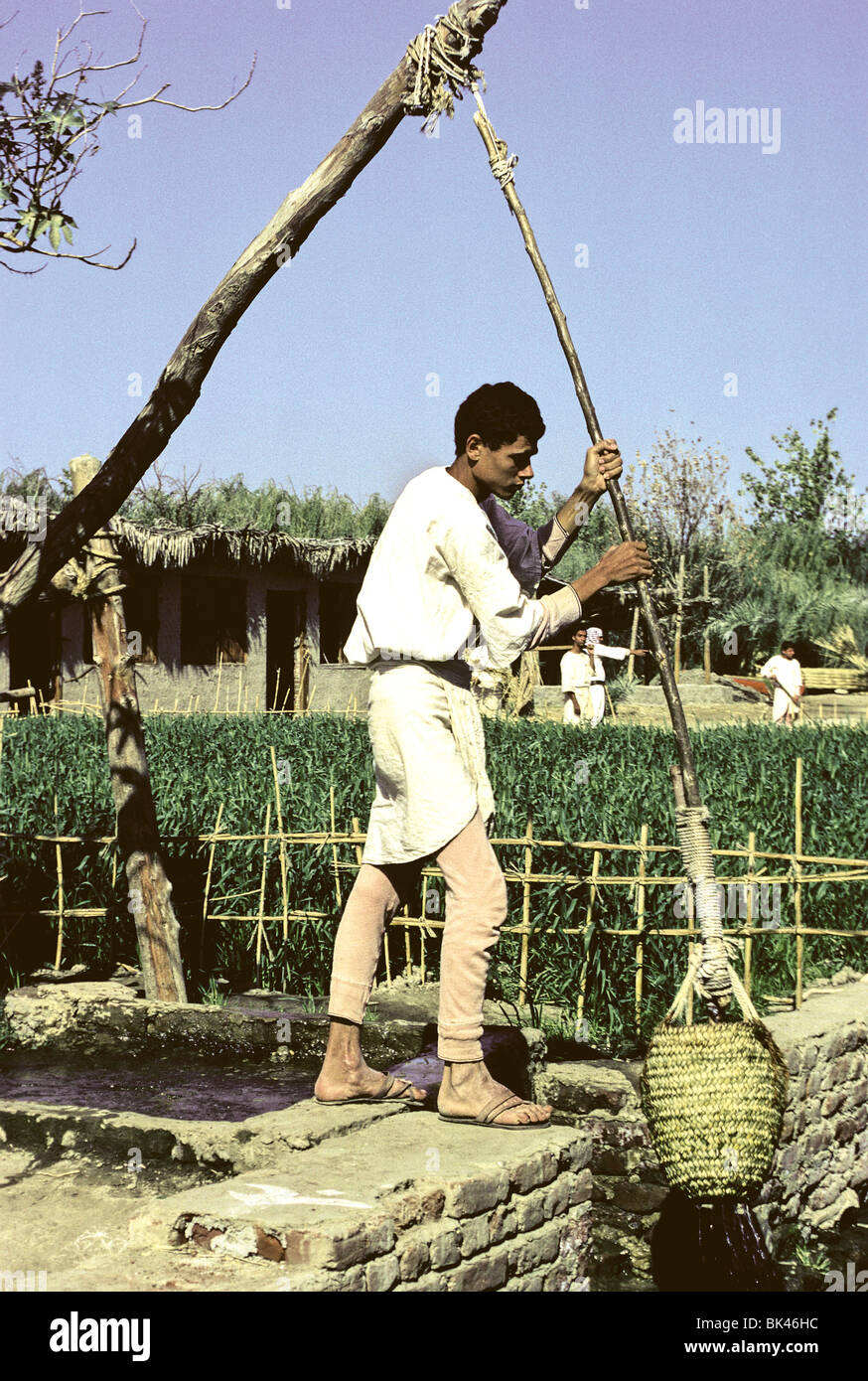 L'homme égyptien à l'aide d'un shadoof historique (outil d'irrigation) au Dr Ragab's Village pharaonique (Living History Museum) au Caire, Egypte Banque D'Images
