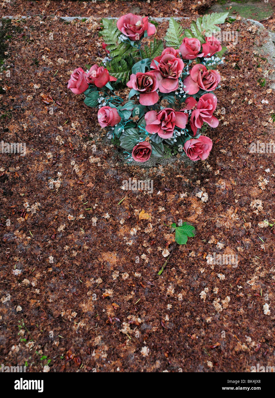 Des fleurs en plastique sur la pierre tombale Banque D'Images
