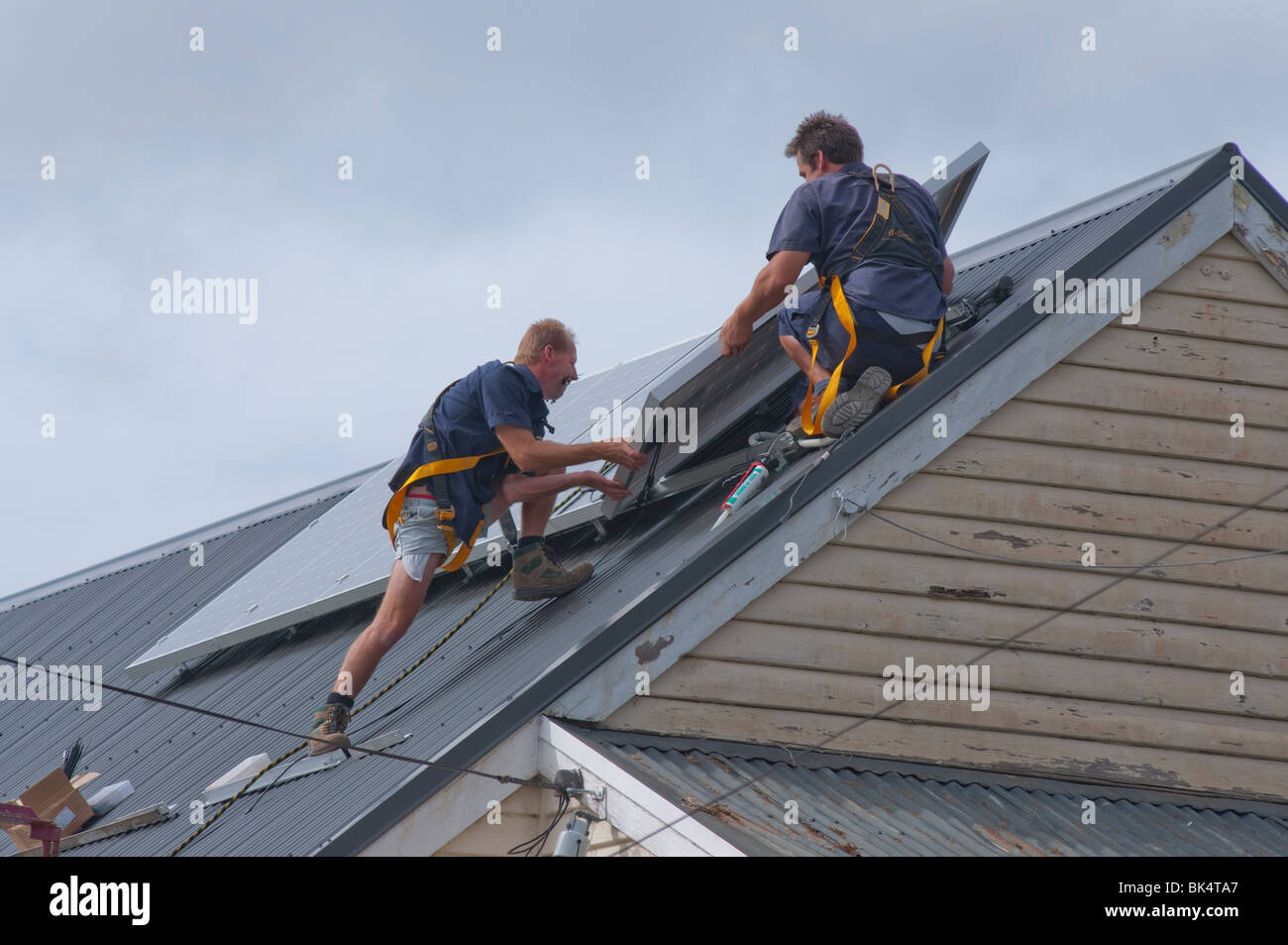 Ouvriers l'installation de panneaux solaires sur le toit d'Hobart Tasmanie Australie Banque D'Images