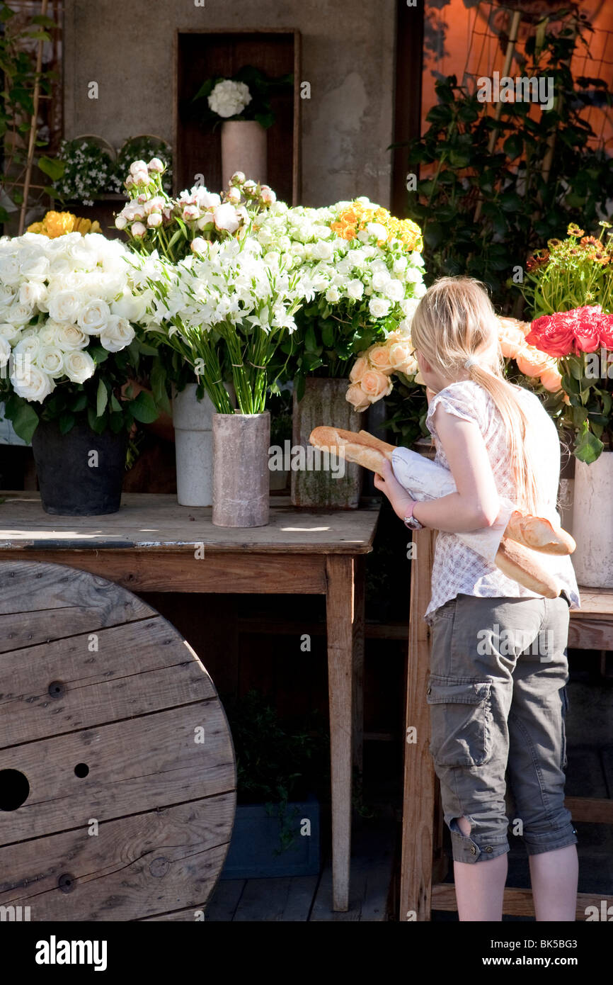 Une femme avec une baguette à Paris France shopping pour les fleurs dans la rue Banque D'Images