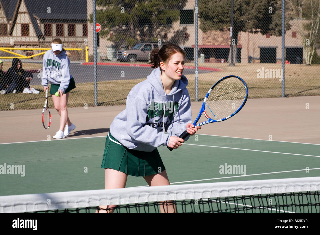 Les jeunes filles du secondaire sur une équipe de tennis de jouer un match sur un après-midi de printemps ensoleillé Banque D'Images