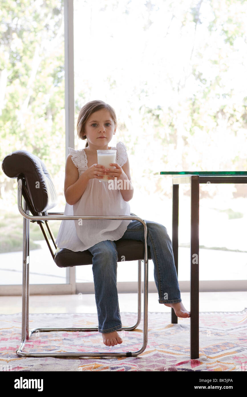 Jeune fille assise dans un fauteuil avec un verre de lait Banque D'Images