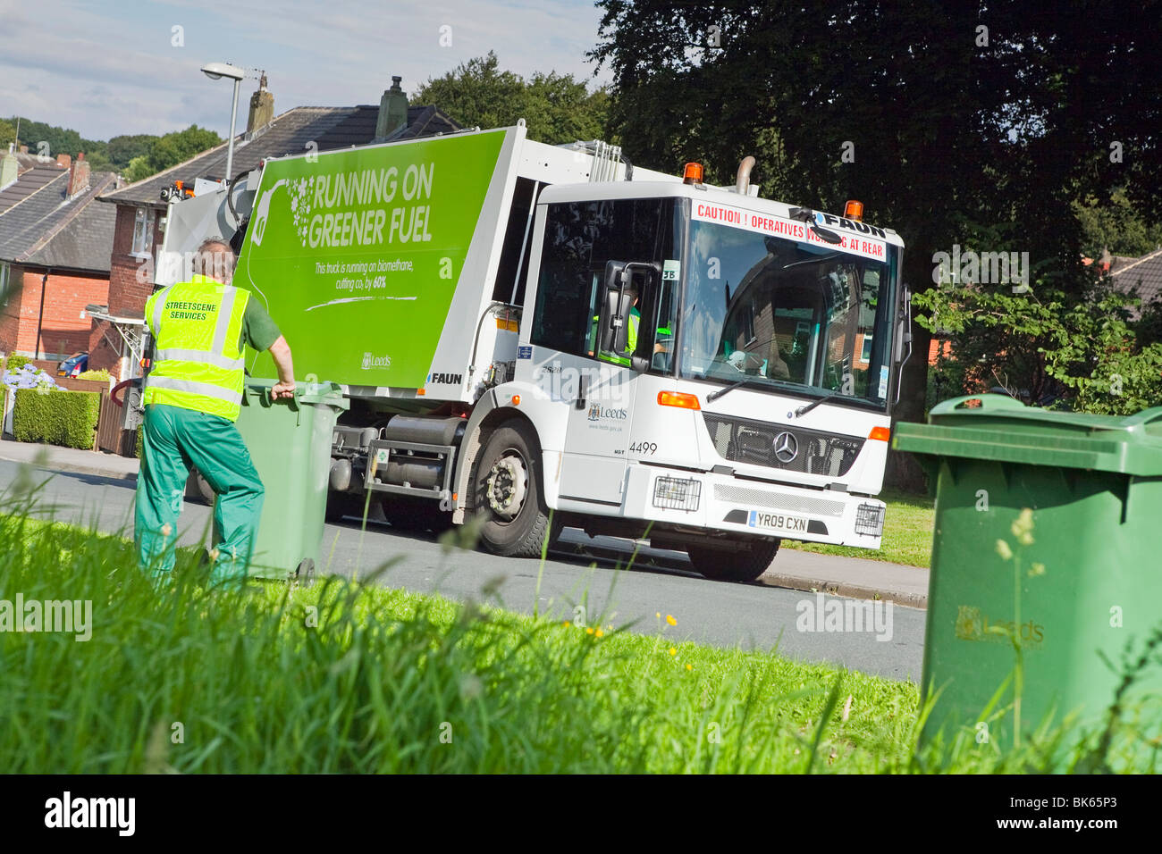 Un gaz powered Econic Mercedes camion benne de collecte des déchets et bin les hommes sur une rue résidentielle Banque D'Images