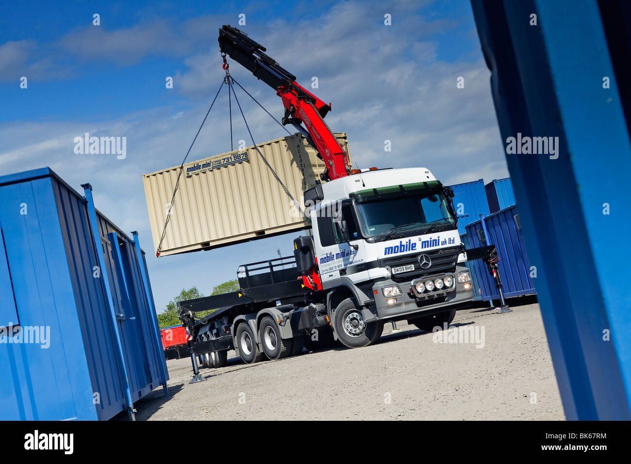 Un camion ou un camion équipé d'une grue qui se lève pour se positionner dans une cour de chantier Banque D'Images
