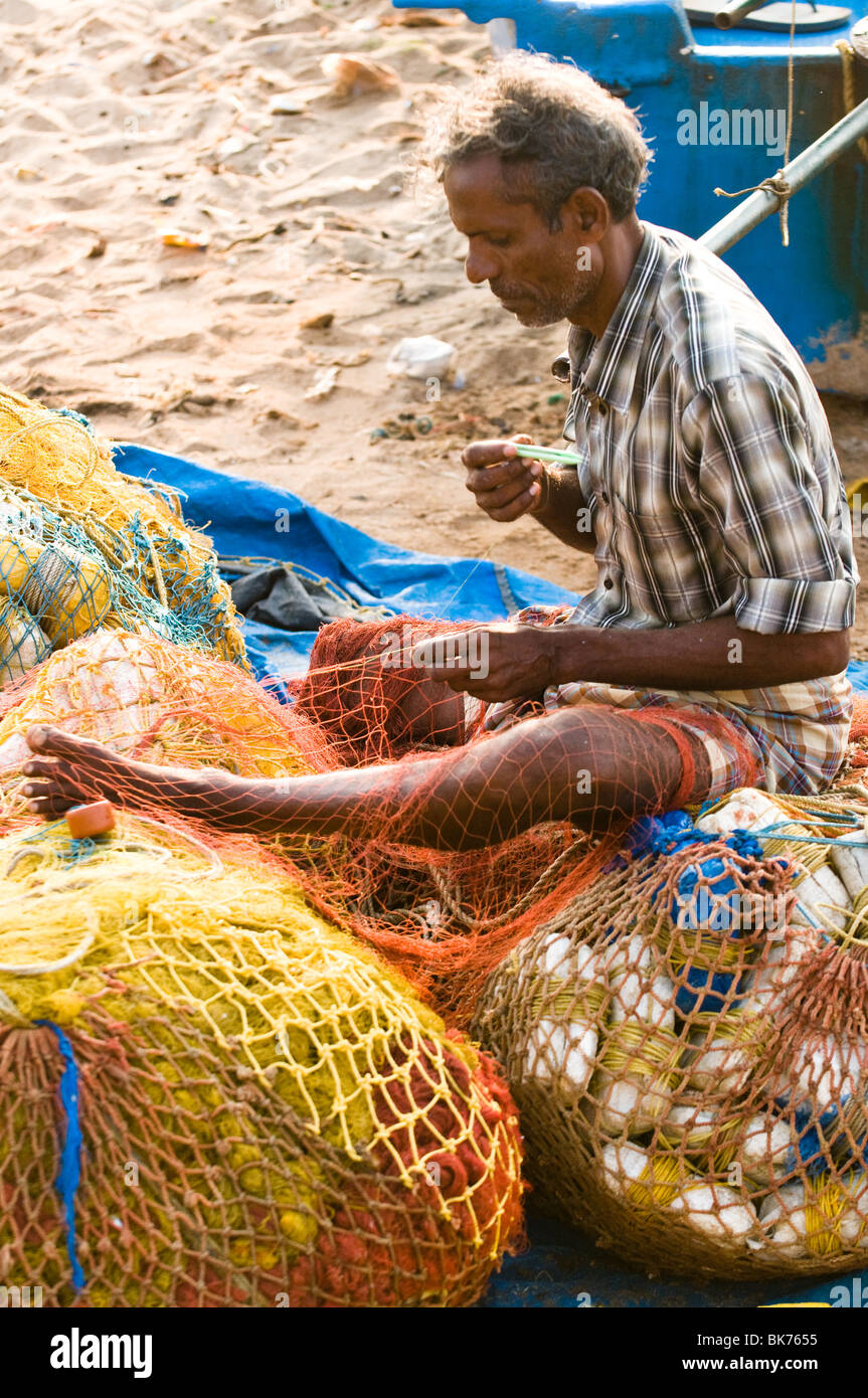 Il s'agit d'une image d'un pêcheur indien du sud raccommodage des filets de pêche. Banque D'Images