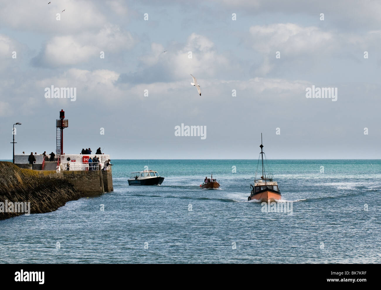 Trois bateaux naviguant au-delà de la jetée banjo à l'entrée de la rivière Looe. Banque D'Images