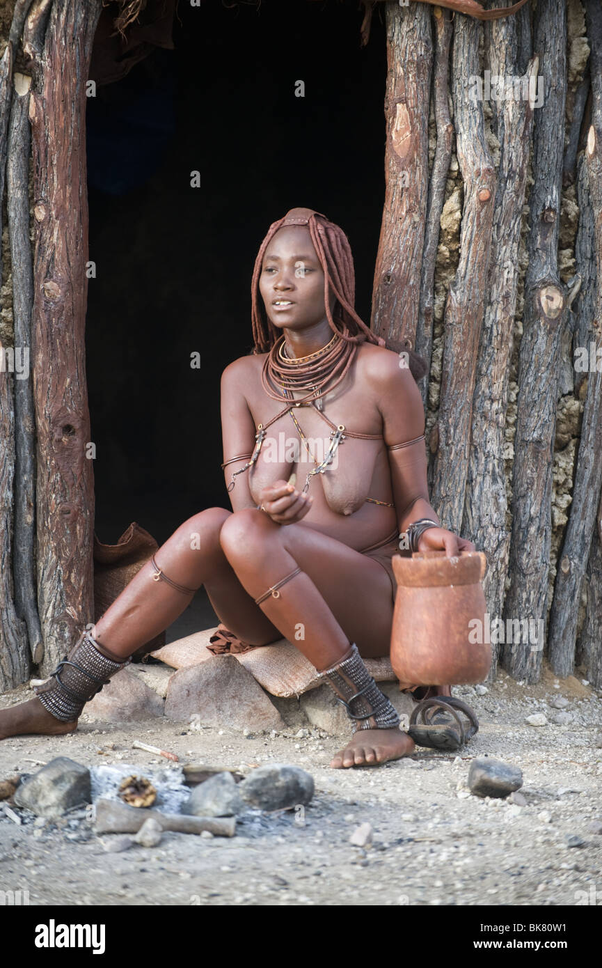 Femme Himba en dehors de sa cabane dans le nord de la Namibie. Banque D'Images