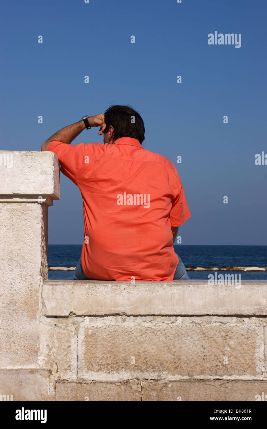 Un homme portant une chemise saumon etait assis en face de la mer Photo Stock Alamy