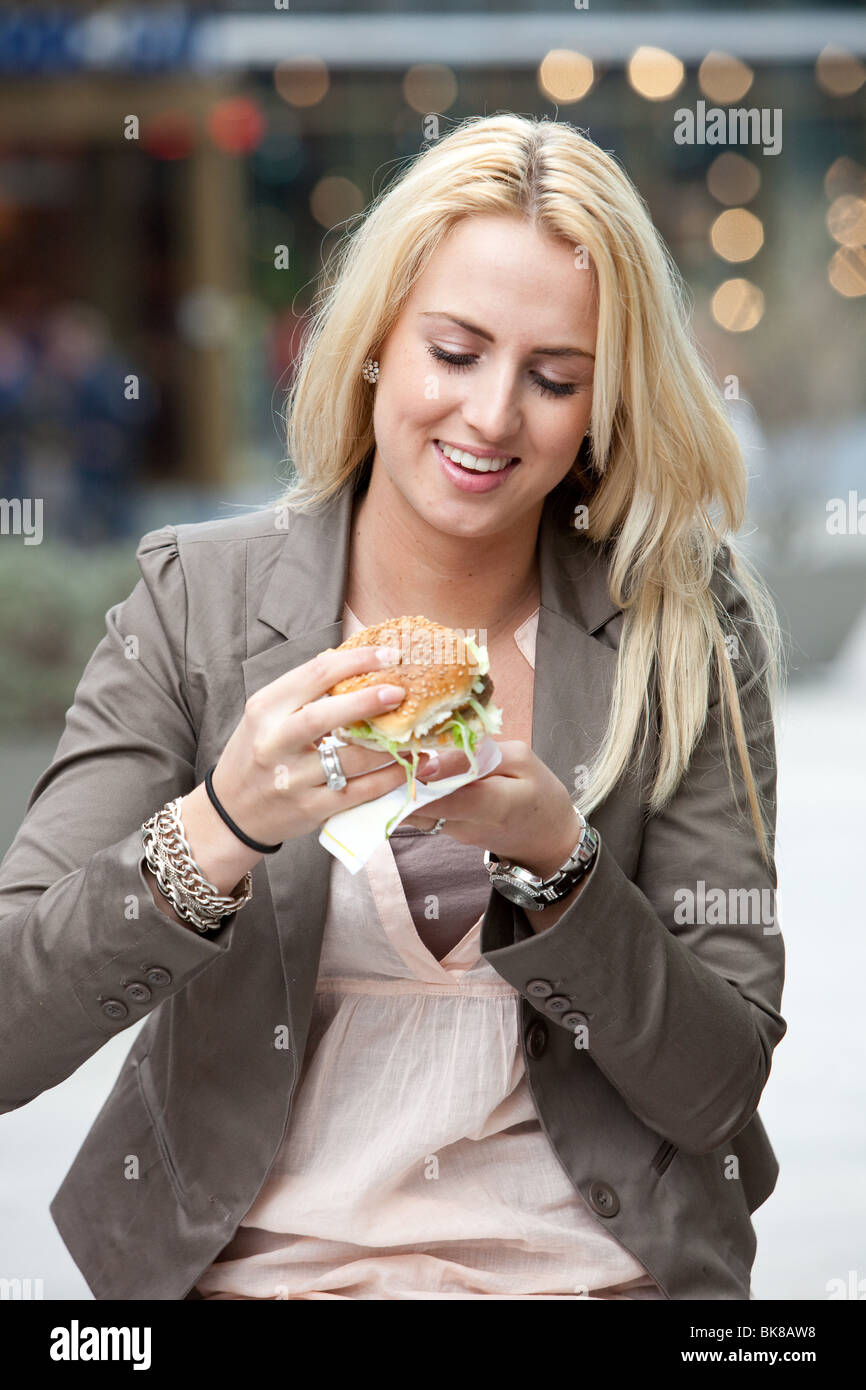 Très jolie jeune femme sur le point de prendre une bouchée dans un hamburger Banque D'Images