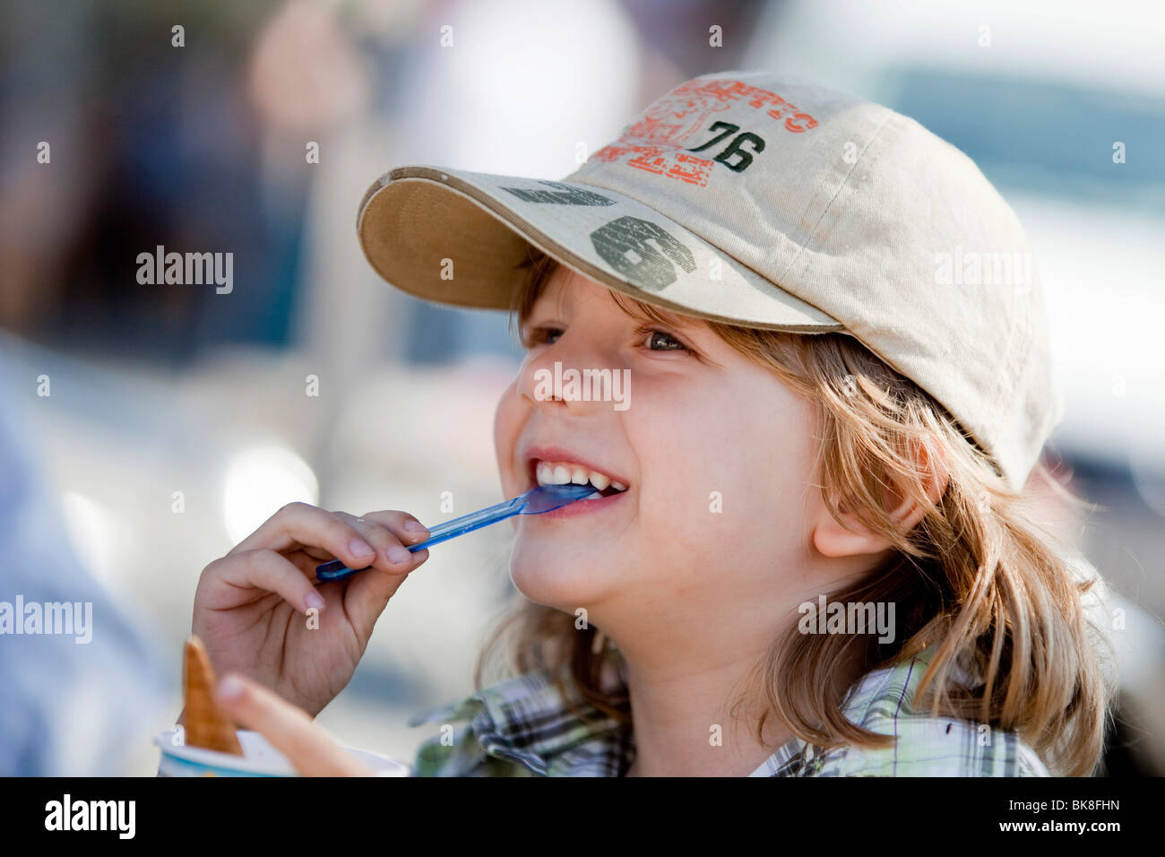 Garçon, trois ans, la consommation de crème glacée avec une cuillère et de rire Banque D'Images