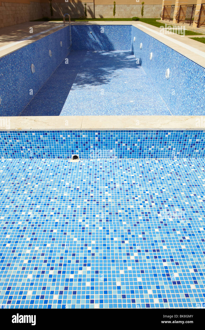 Sol carrelé bleu piscine vide sur une journée ensoleillée sans eau Banque D'Images