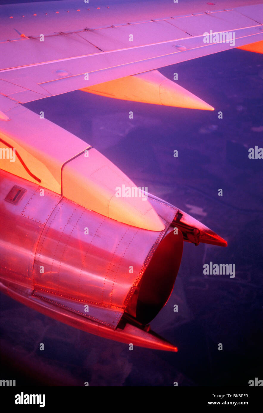 Coucher de soleil illumine l'aile et moteur à réaction d'un avion commercial avec des couleurs roses et rouges de la lumière Banque D'Images