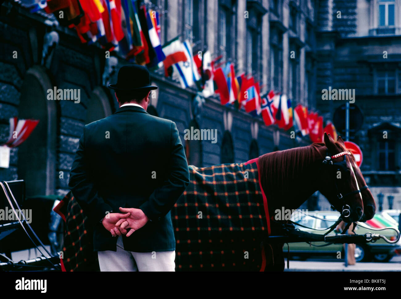 Conducteur de chariot et l'attente de clients sous les drapeaux multi pendaison dans une rangée sur une façade de l'immeuble, Vienne, Autriche Banque D'Images