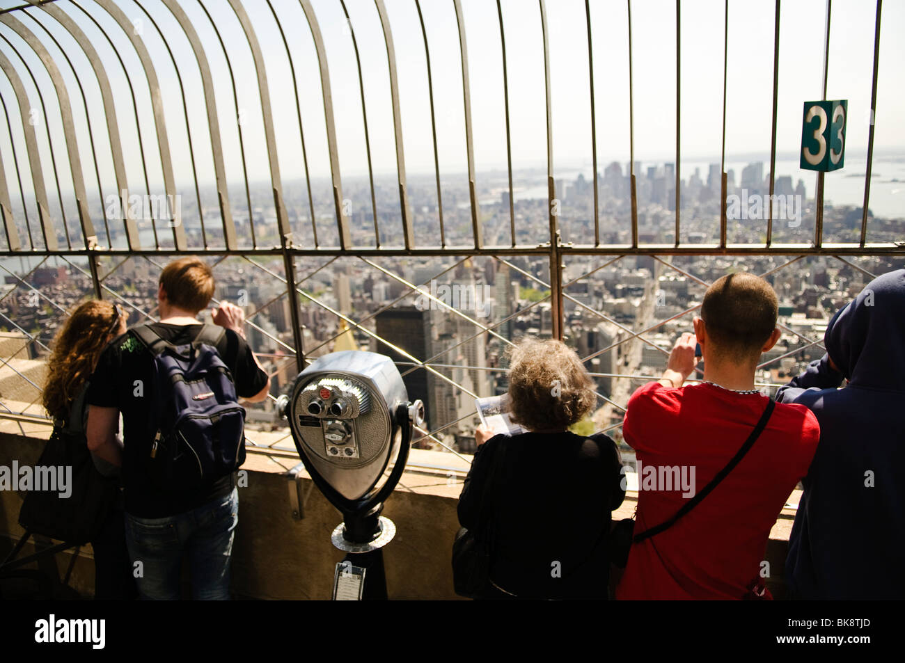 NEW YORK, NY, États-Unis — les touristes admirent la vue depuis le sommet de l'Empire State Building à New York par un clair jour de printemps. La terrasse d'observation offre une vue panoramique imprenable sur Manhattan et au-delà, ce qui en fait l'une des attractions touristiques les plus emblématiques de la ville. Banque D'Images