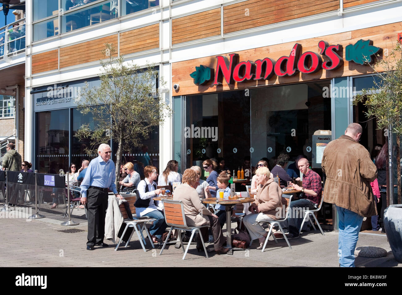 Les personnes mangeant à l'extérieur à Nando's Cafe, la baie de Cardiff, Pays de Galles, Royaume-Uni. Banque D'Images